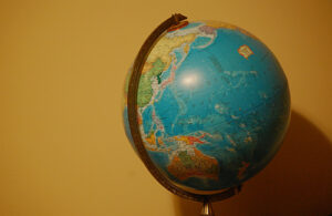A globe stands in front of a bright yellow wall. Australia and parts of Asia can be seen on the globe.