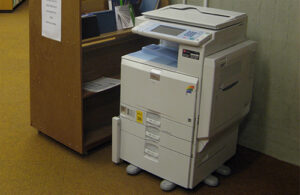 A photocopier sits alongside a book Loughborugh University Library. returns cart at the