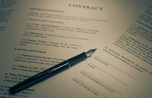 A black fountain pen lays on top of pages of a contract.