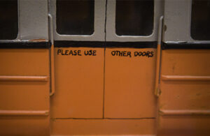 Orange train doors with 'Please use other doors' painted by hand on the doors.