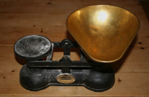 A set of kitchen scales on top of a wooden bench.