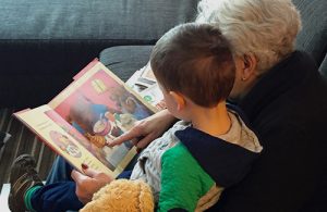 A grandmother and her grandson sit together reading a picture book.