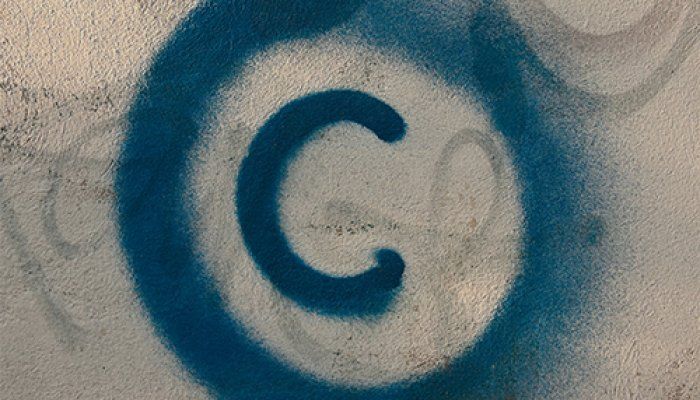 A blue copyright symbol is spray painted on a cream-coloured wall.