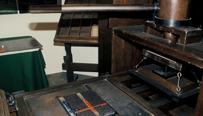 A photo of a replica Guttenberg printing press setup to print a page from the bible.