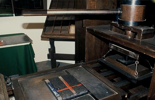 A photo of a replica Guttenberg printing press setup to print a page from the bible.